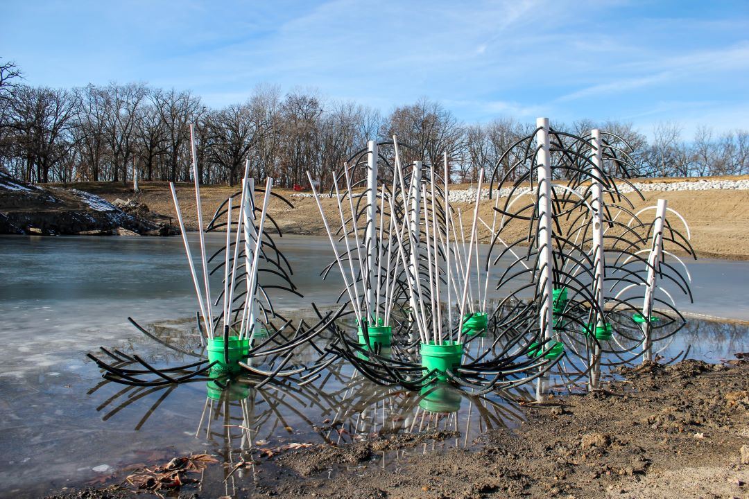 Plastic pipes extend from buckets to create fish habitat inside empty McFarland Lake