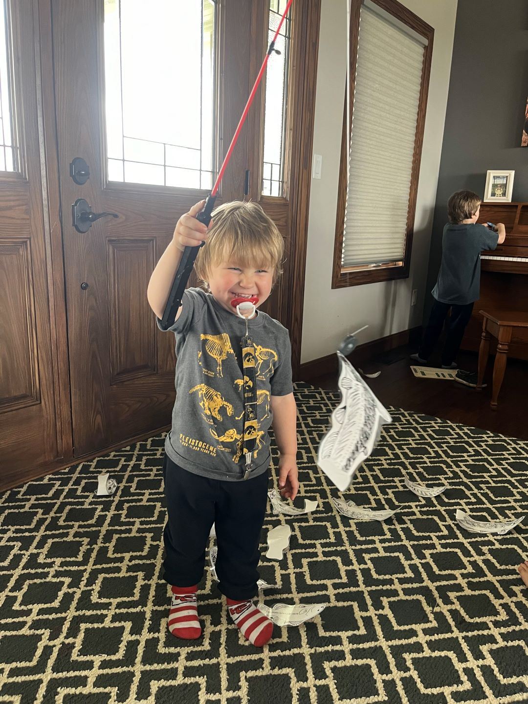 Young boy smiles as he caught paper fish with fishing pole during activity