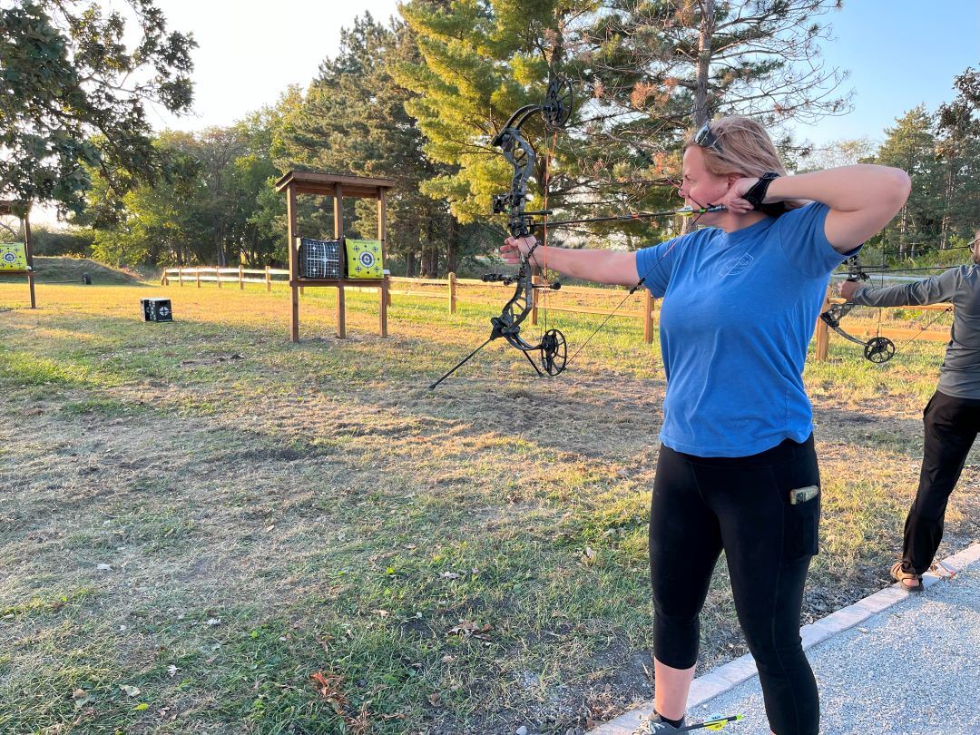 Woman aiming bow at target at new Archery Range