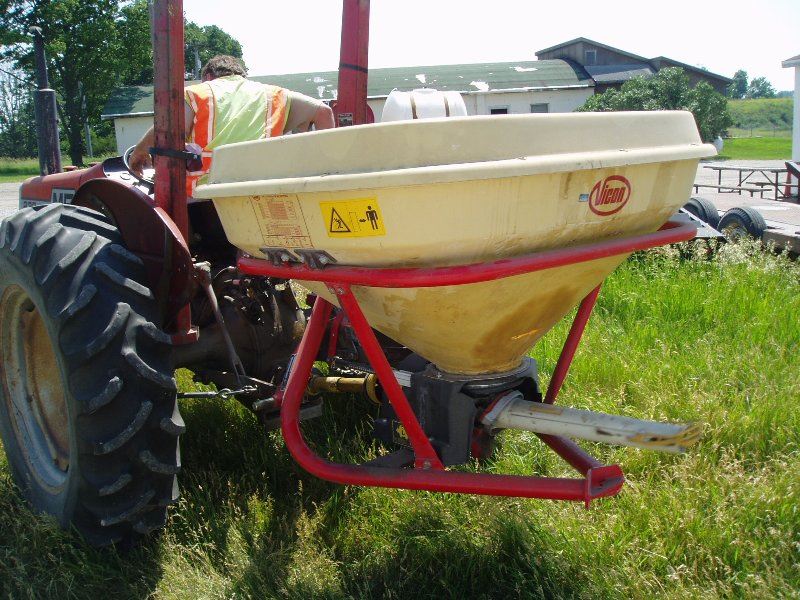 White and red broadcast seeder hooked to tractor