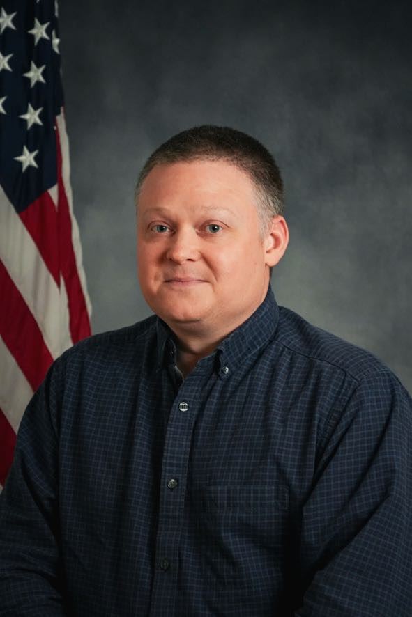 Headshot of Colin Gerst, IT Director, in front of the american flag