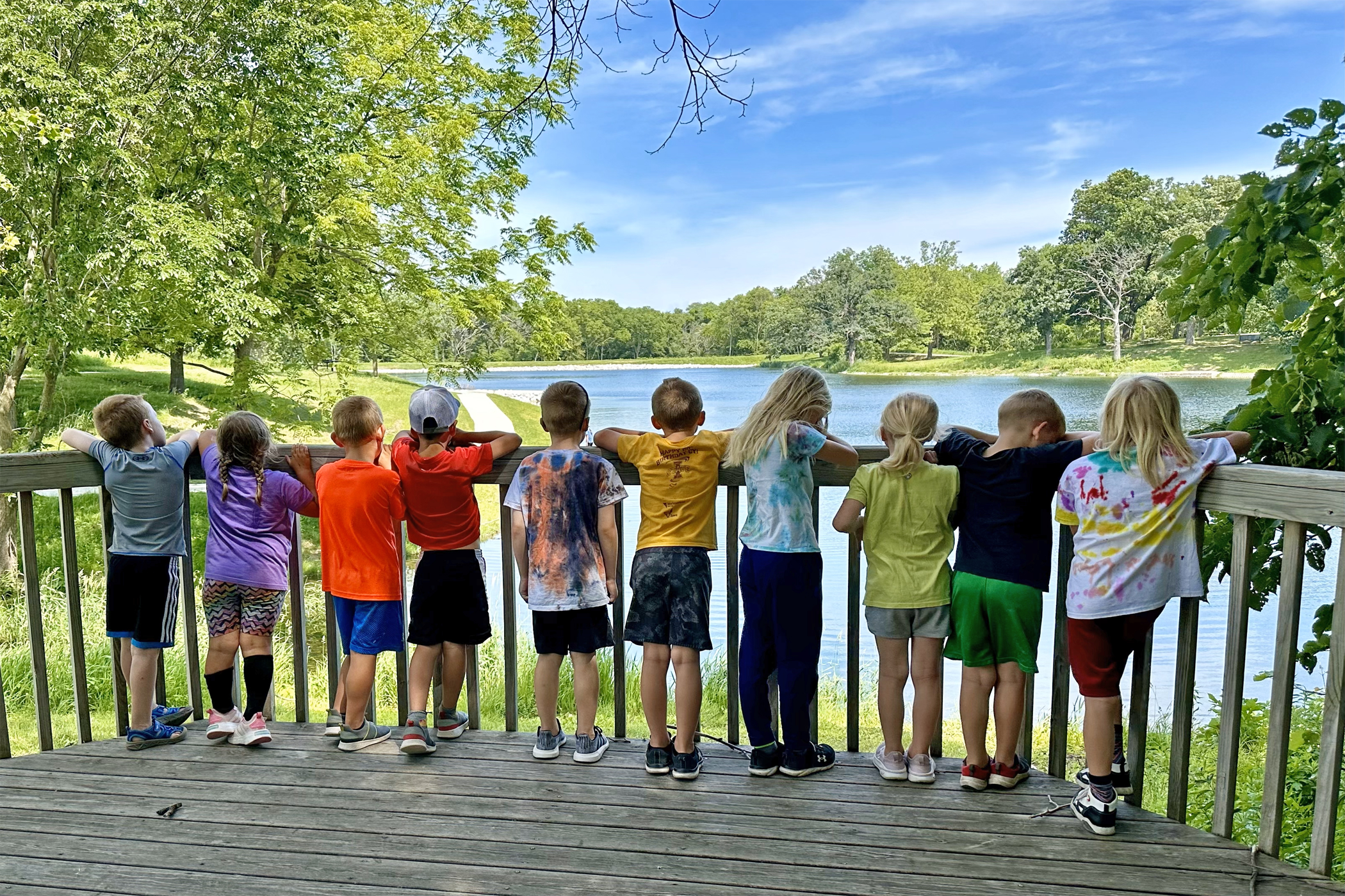Group of kids stand on deck at McFarland Park lake